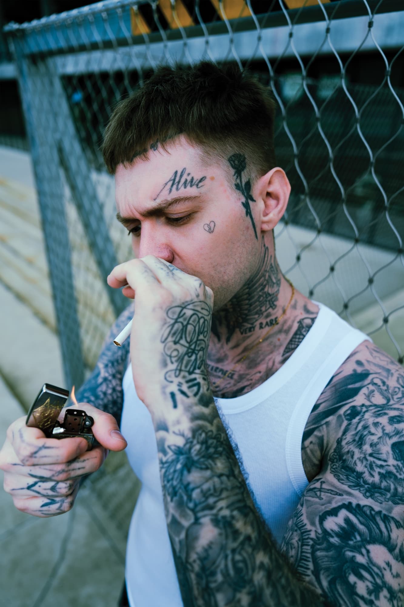 „Alive“ virš antakio – prisidegama tinklinės tvoros fone.