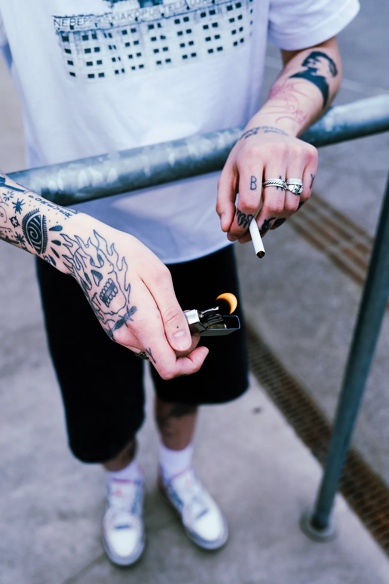 Tattooed forearms at a steel rail – flaming skull on the hand, BAY across the knuckles.
