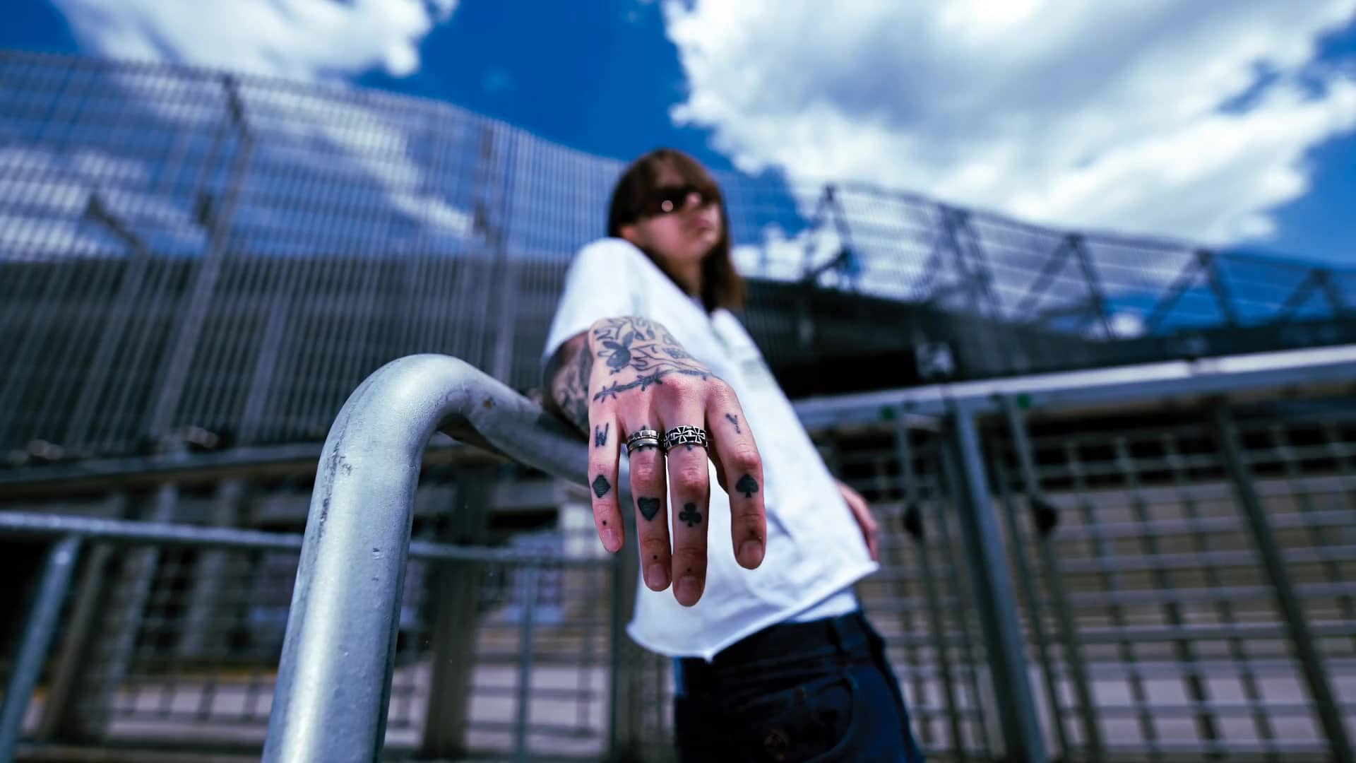 Tattooed hand extended toward the lens scatters dice toward the camera.